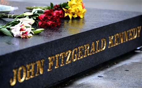 Flowers are placed on the granite marker that reads "John Fitzgerald Kennedy," located within the John F. Kennedy Memorial Plaza in Dallas, Texas.