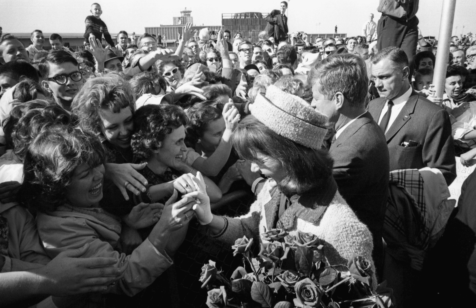 En un movimiento imprevisto, el presidente Kennedy caminó hacia la gran multitud que esperaba en Love Field después de saludar a la fila de dignatarios locales. Los Kennedy y los Johnson se estrecharon la mano e intercambiaron saludos con la ansiosa multitud, para deleite de ambos. Colección del Dallas Times Herald / Museo de la Sexta Planta en Dealey Plaza